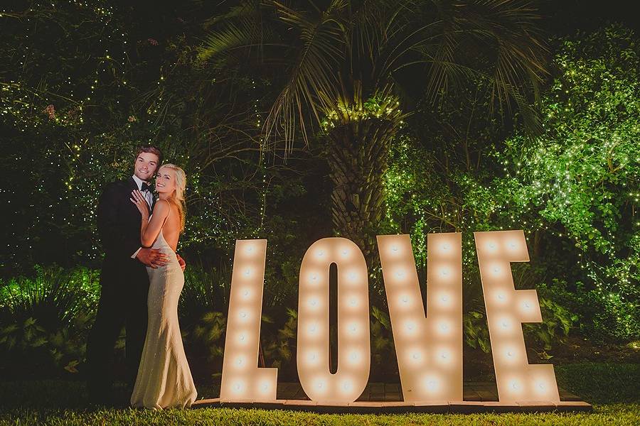 Couple poses by lit sign outside