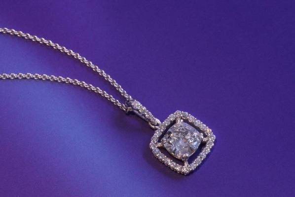 Bridal necklace made of platinum with a cushion shaped center diamond surrounded by round diamonds