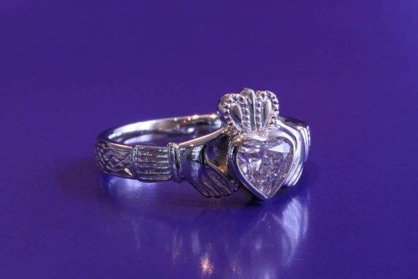 Platinum claddagh engagement ring with hand engraving.  The heart shaped diamond is set within a bezel frame.