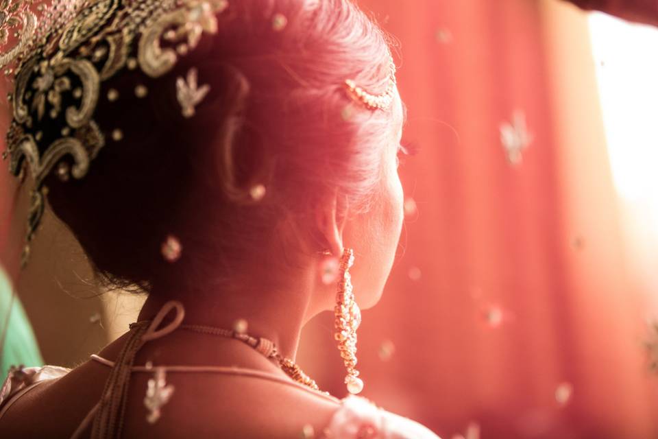 Indian bride's hair decorated with flowers, gold jewelry and the traditional red cloth