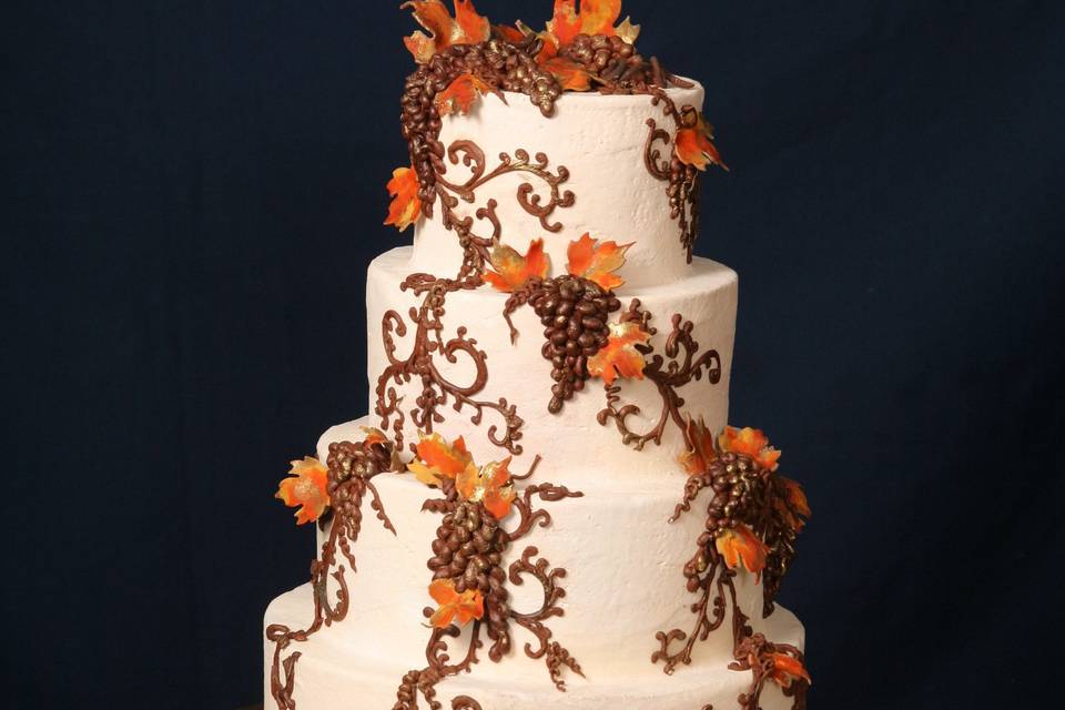 Italian Buttercream wedding cake decorated with chocolate grapes and vines with bright colored sugar leaves.