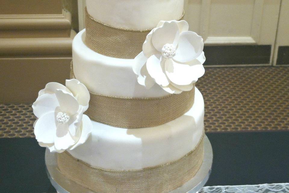 A 3 tier Nashville Wedding Cake covered in fondant,surrounded in  burlap ribbon