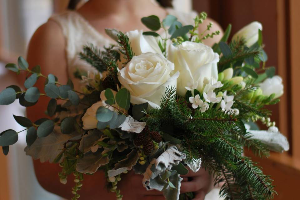 Winter bouquet of fir, cedar, white roses, white tulips, white freesia, white bridal pearls, and eucalyptus.