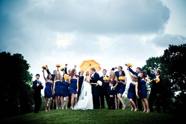 Newlyweds with wedding attendants and umbrellas