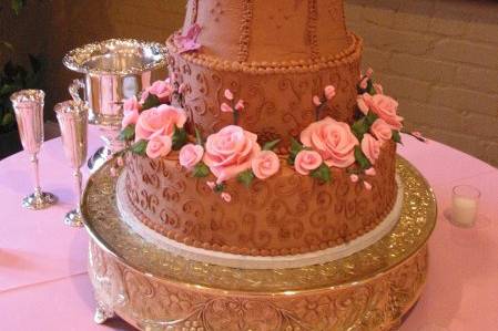 A chocolate lover's masterpiece iced in chocolate buttercream.  Pink hand-made sugarpaste roses and buds enhance a design which includes a sculpted middle tier.