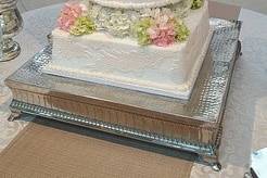 Tall multi-shaped cake with lace and hydrangeas in the atrium of the Columbia Museum of Art.