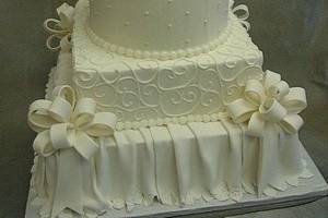 White multi-shaped tower.  All buttercream except for bows, monogram plaque and bottom tier skirt.