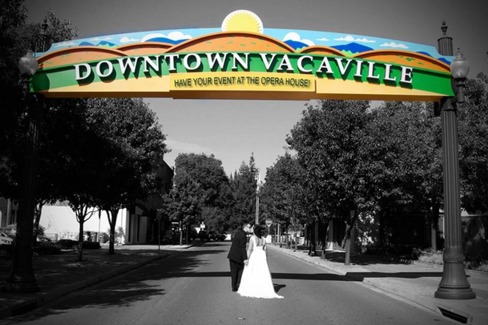 Photography by Kelly MurrayBride and groom under Vacaville sign on Davis st. Opera House in background to the left.